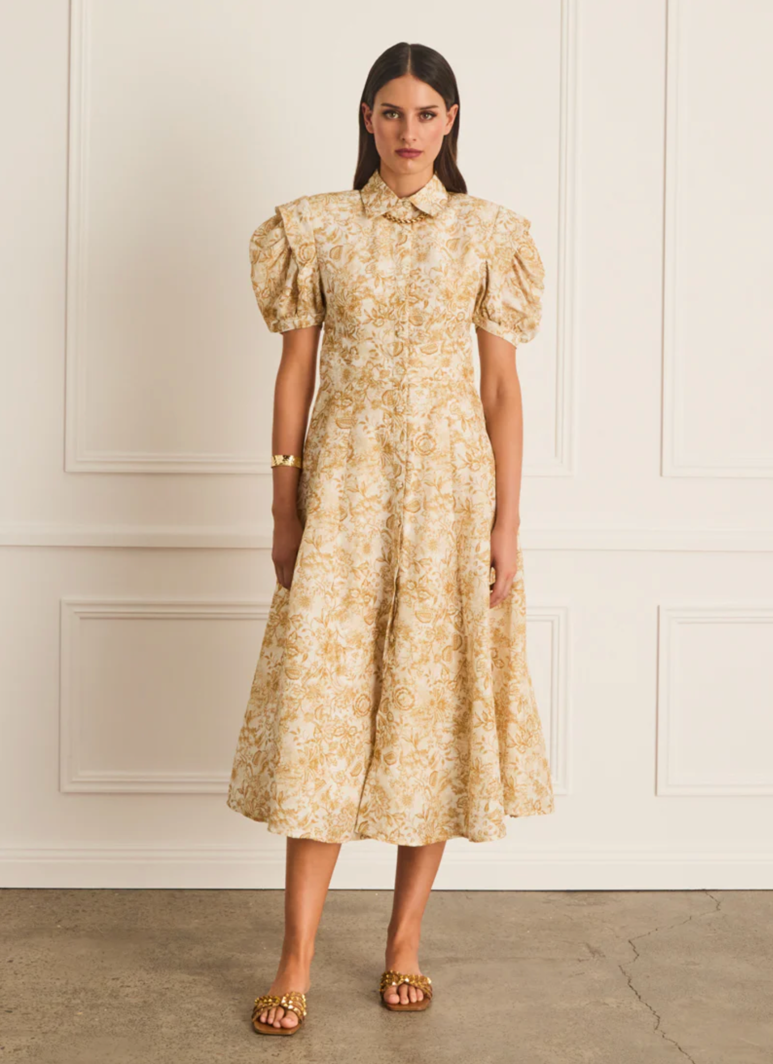 Woman wearing a floral dress against a white wall