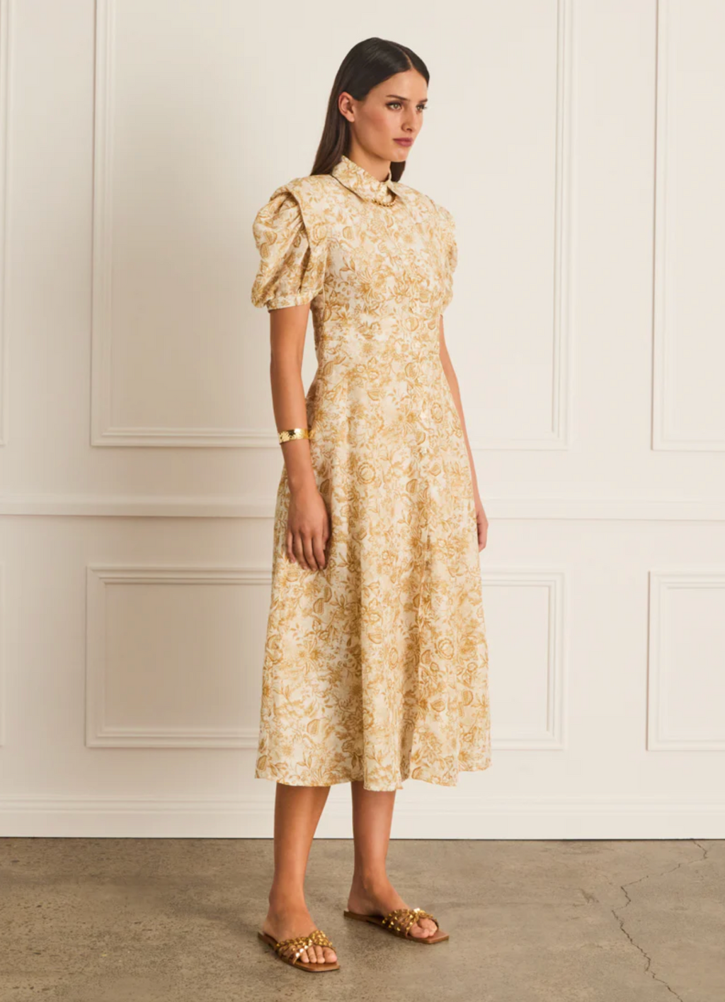 Woman wearing a floral dress against a white wall
