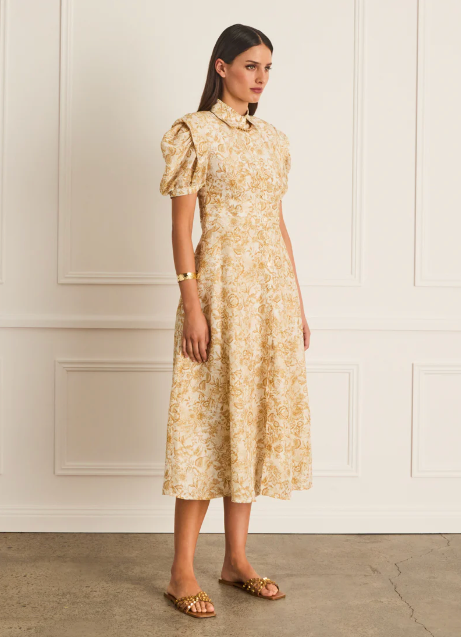 Woman wearing a floral dress against a white wall